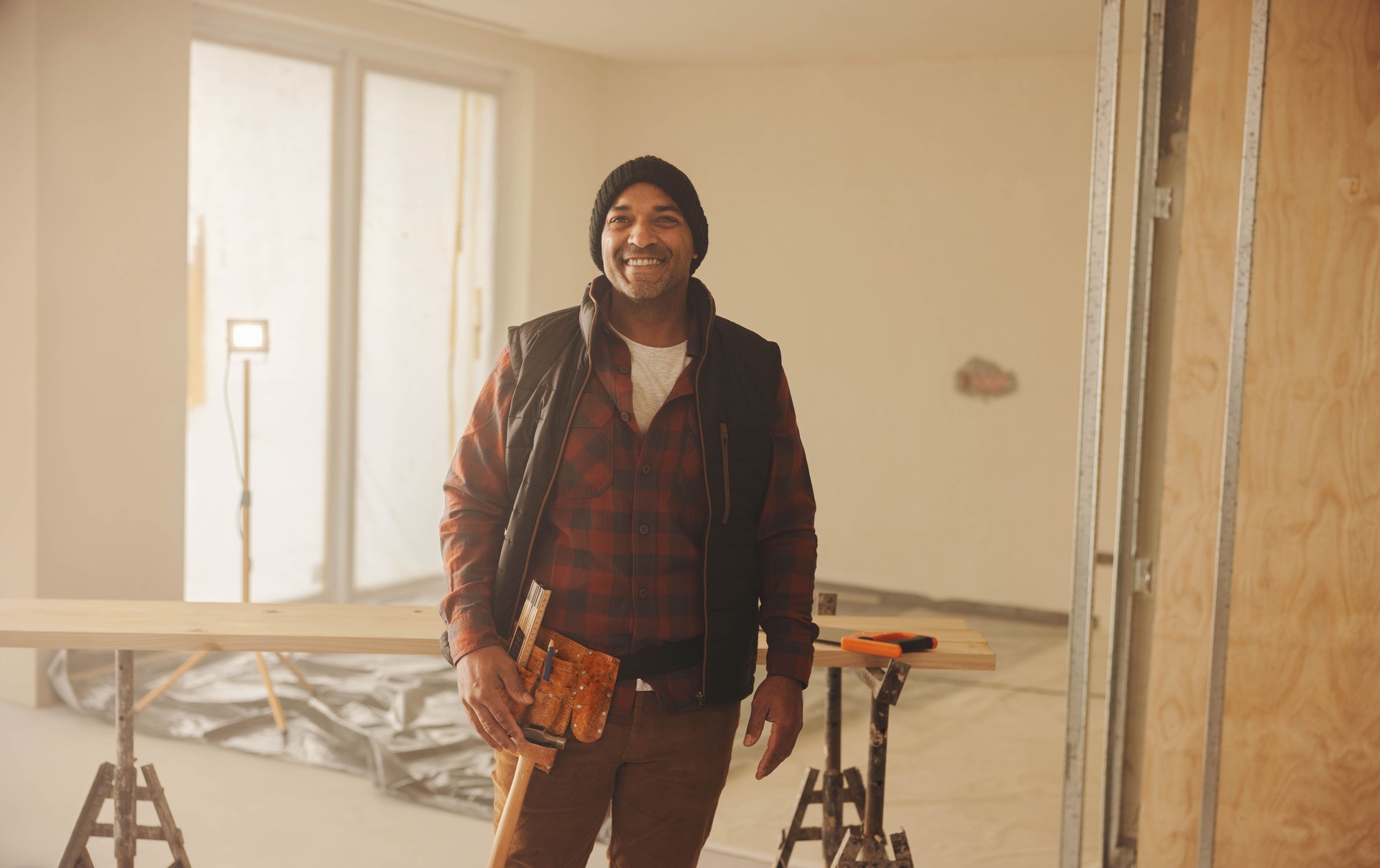 Happy carpenter wearing a tool belt and smiling during a home renovation
